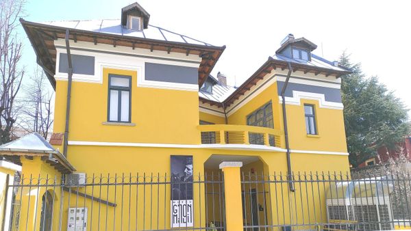 Pamje e jashtme e Muzeut «Gjon Mili» në Korçë, një vilë e verdhë neoklasike me baner të fotografit në fasadë