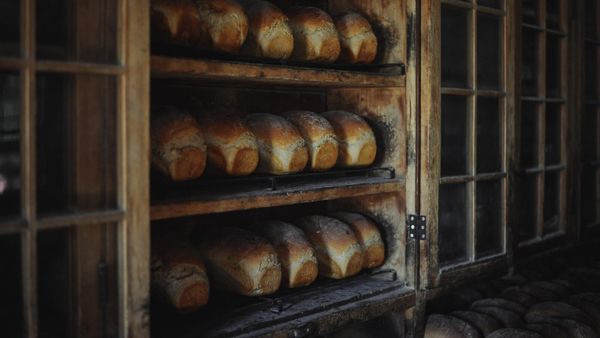 Bukë e sapopjekur në raftet prej druri të një furre