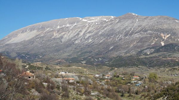 Mal i lartë gëlqeror me pak dëborë, parë nga fshati Nivicë i Kurveleshit, me shtëpitë e fshatit në plan të parë