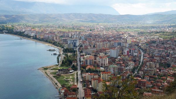 Pogradeci i shtrirë buzë Liqenit të Ohrit, parë nga kodra e kalasë, me rrugën kryesore dhe bregun e liqenit