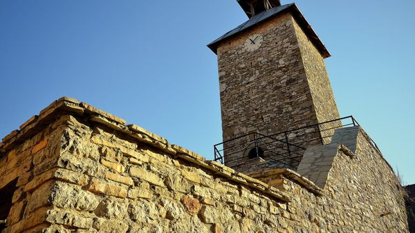 Sahat Kulla e Rahovecit, kullë guri me fushë ore të bardhë dhe kambanore me çati, mbi një mur të vjetër guri, nën qiell të kaltër