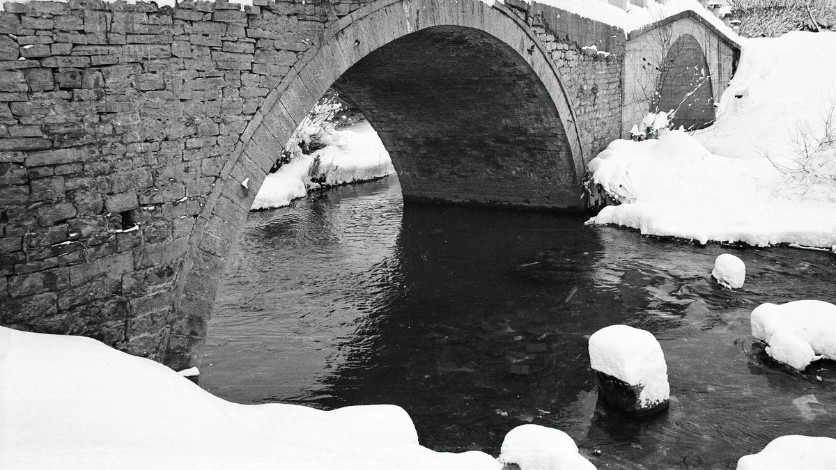 Ura e vjetër me hark guri mbi lumin Klina, me brigjet të mbuluara me dëborë