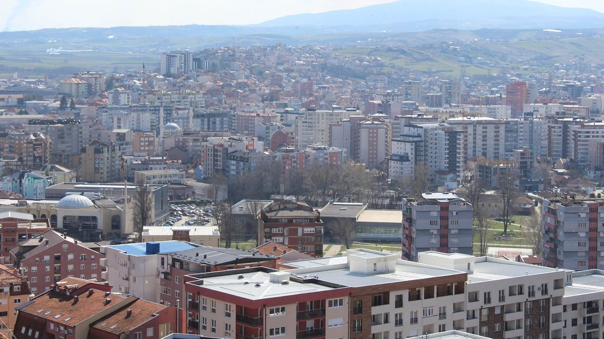 Pamje panoramike e Mitrovicës, me pallate banimi, çati të kuqe dhe kodra në horizont