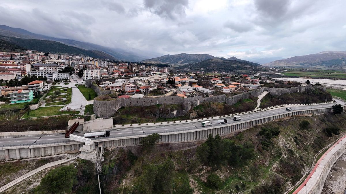 Pamje nga ajri e mureve të kështjellës së Tepelenës me shtëpitë brenda tyre, qytetin pas tyre, rrugën poshtë dhe luginën e Vjosës djathtas