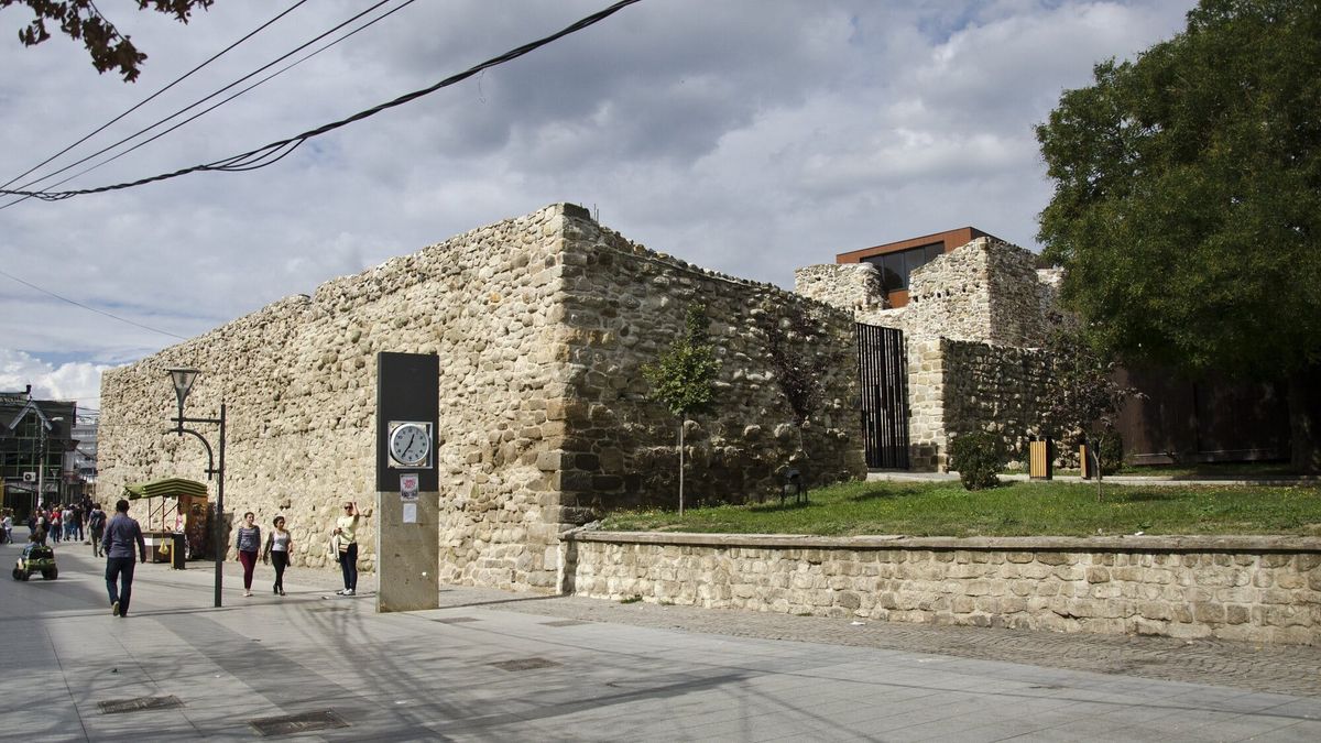 Muret prej guri të kalasë së Vushtrrisë dhe kulla e saj në qendër të qytetit, me një shesh të shtruar ku ecin kalimtarë